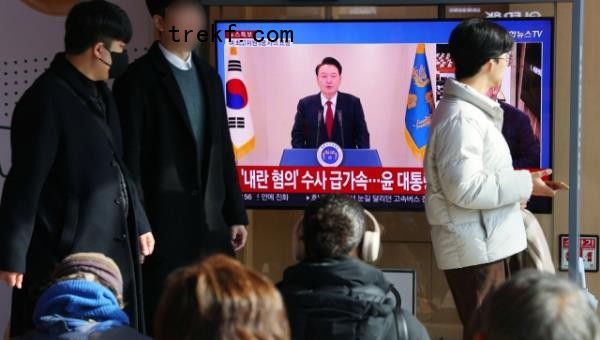 Commuters at Seoul Station watch President Yoon Suk Yeol<em></em>'s public address on TV, Dec. 12. (Yonhap)
