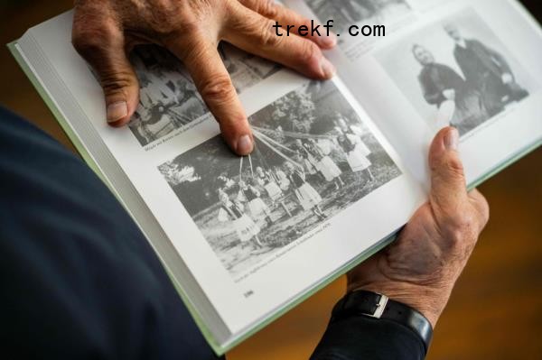 Michael Lisske points with his finger on an old photograph showing his wife, Carmen Schuster, as a young local girl taking part in a celebration in Cincsor, a small Transylvanian village some 250km north-west of Bucharest October 17, 2024. — AFP pic